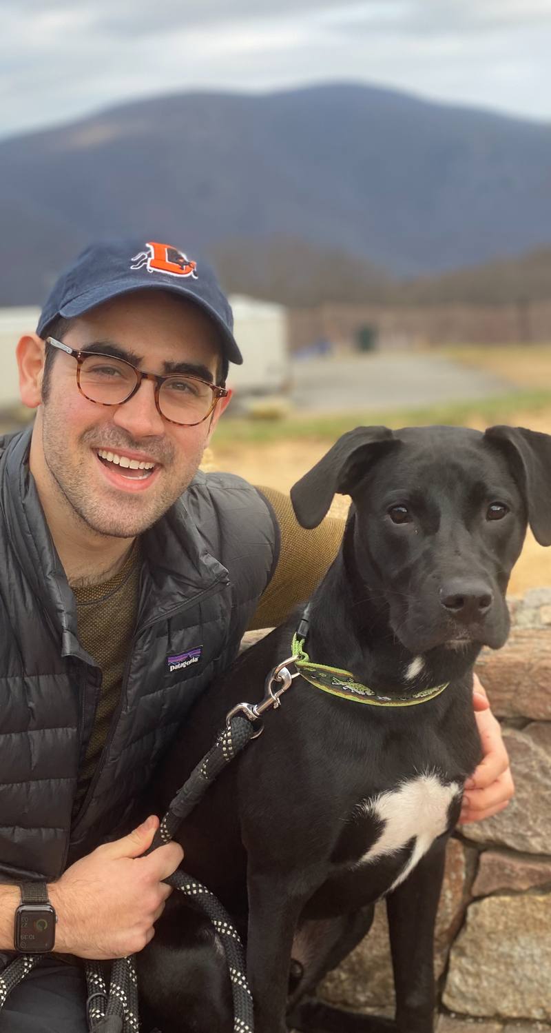 Illustrator Nick Cook smiling with his black Labrador