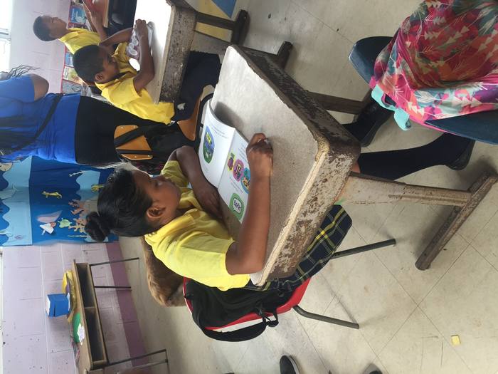 A student reading the book at her desk in a classroom